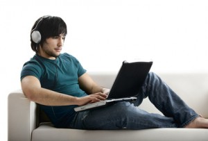 Ein junger Mann sitzt auf einem Sofa und schaut sich Videos auf YouTube an