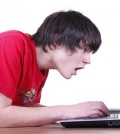Ein Junge guckt entsetzt auf seinen Laptop