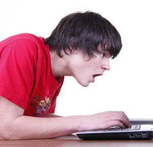 Ein Junge guckt entsetzt auf seinen Laptop