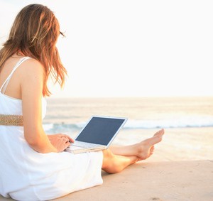 Frau am Strand mit einem Ultrabook